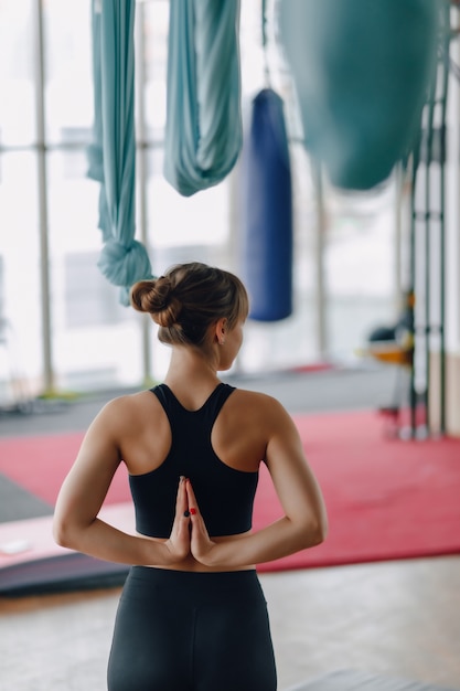 Hands folded behind her back, girl in gym during yoga class