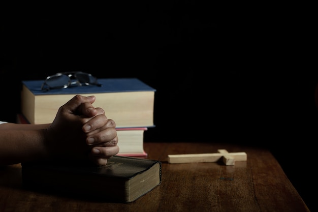 Hands folded in prayer on a Holy Bible in church 