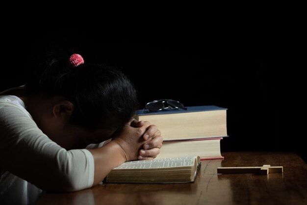 Hands folded in prayer on a Holy Bible in church 