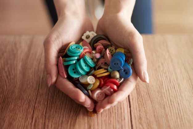 Foto gratuita mani piene di bottoni colorati