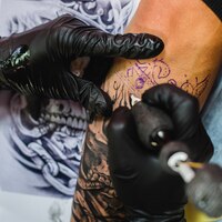 Free photo hands in gloves doing tattoo