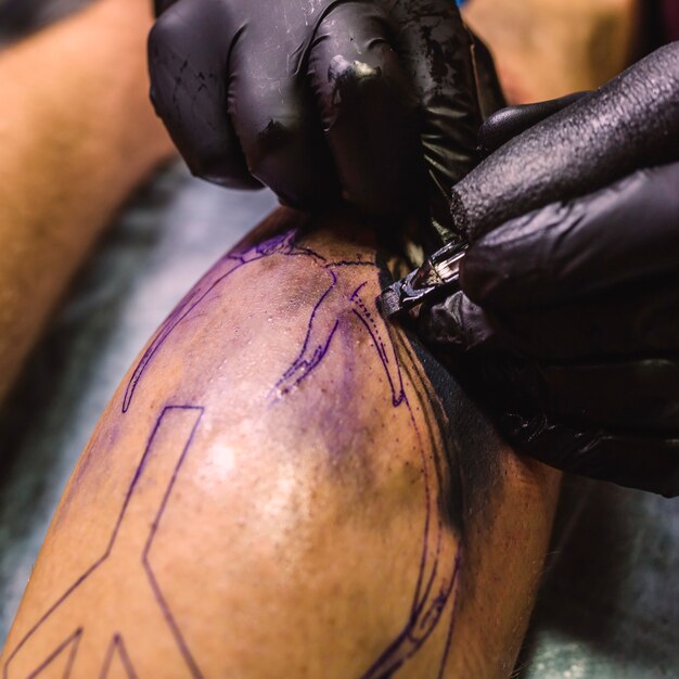 Hands in gloves making tattoo