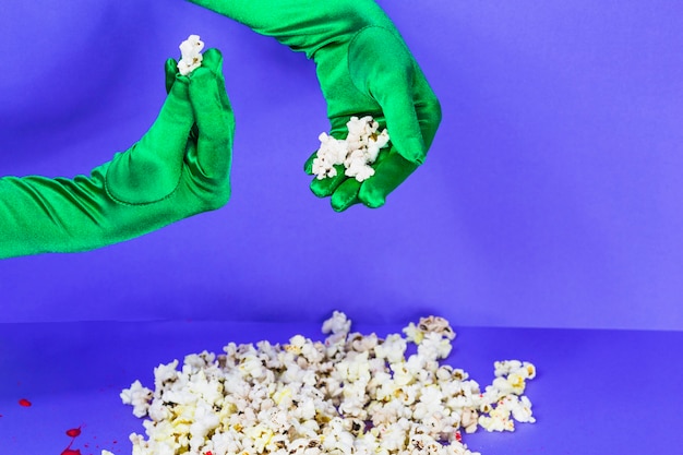 Hands in green gloves holding popcorn