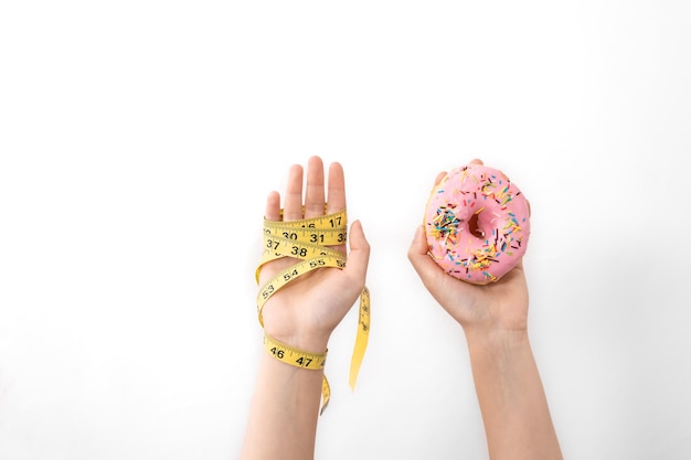 Hands hold donut and measuring tape on white isolated copy space