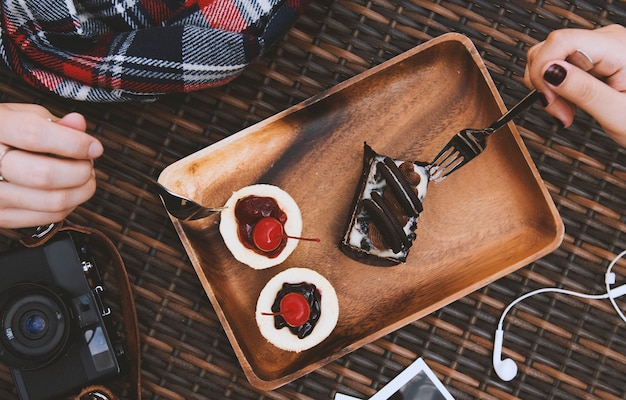 Le mani tengono le forcelle che mangiano le torte dolci