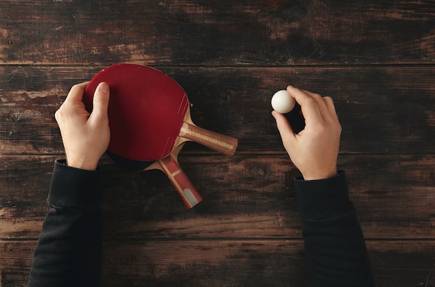 Hands hold two professional ping pong rockets, attack plus and defense