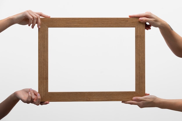Free photo hands holding big wooden frame