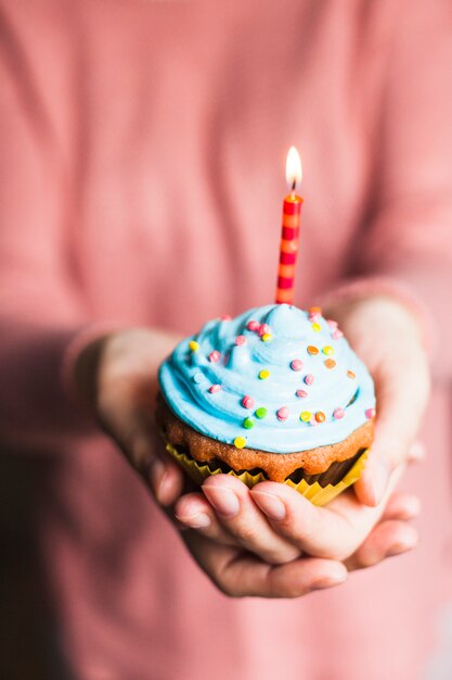 Mani che tengono il muffin di compleanno