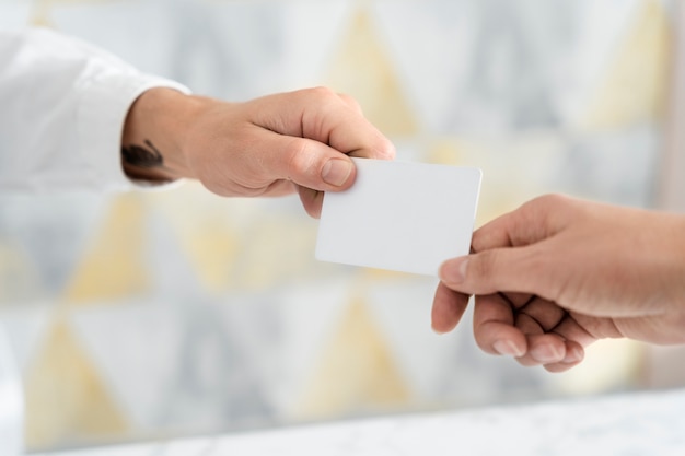 Hands holding blank business card at office