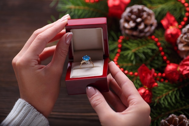 Mani in possesso di una scatola con un anello con una pietra blu