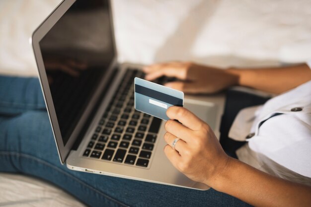 Hands holding a card and working on laptop