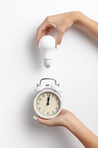 Hands holding clock and light bulb