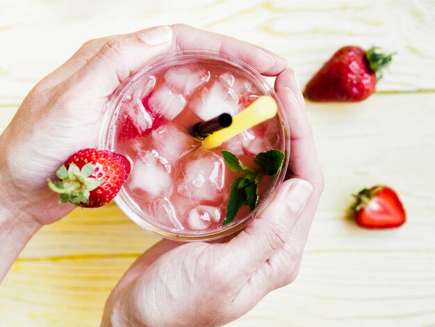 Hands holding cold cup of strawberry drink