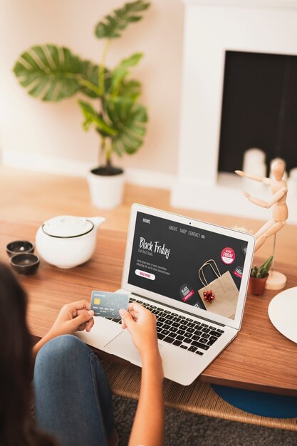 Hands holding a credit card next to a laptop mock up