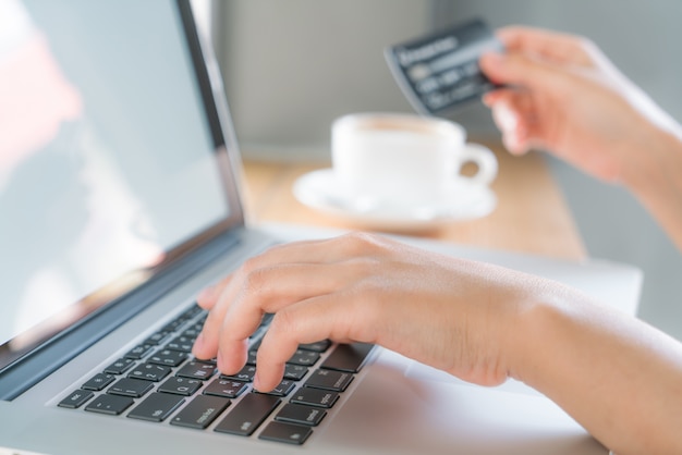 Free photo hands holding a credit card and using laptop computer for online