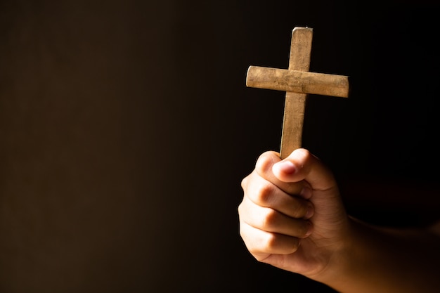 Free photo hands holding cross while praying.