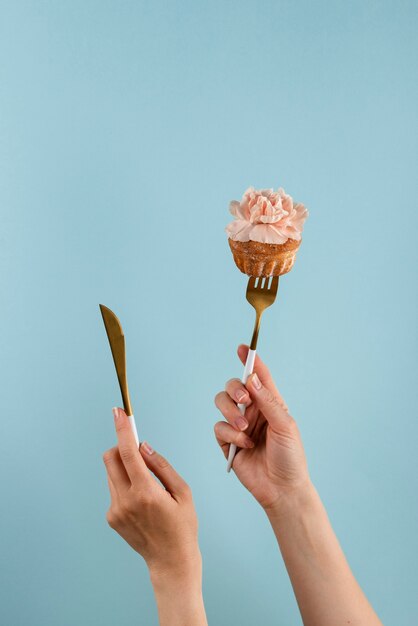 Hands holding cutlery with cupcake