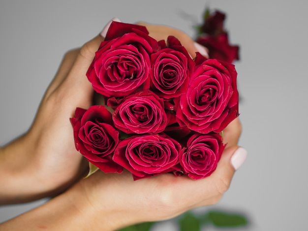 Foto gratuita mani che tengono delicato bouquet di rose