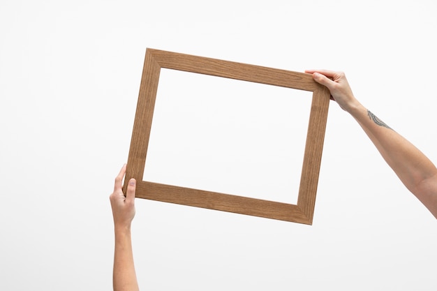 Free photo hands holding empty big wooden frame