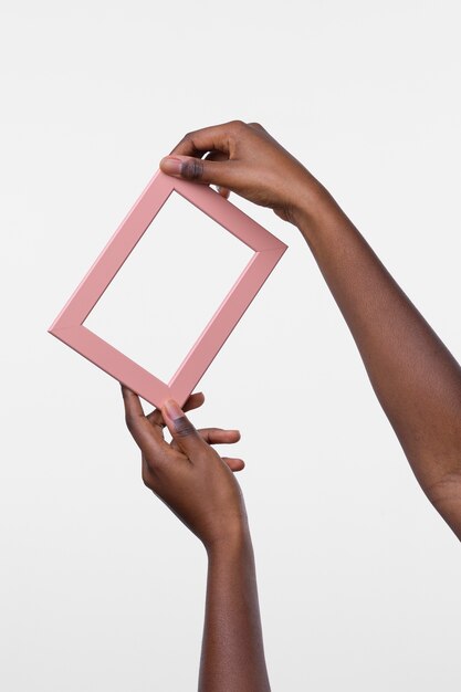 Free photo hands holding empty pink frame
