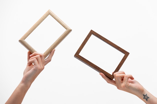 Free photo hands holding empty wooden frames