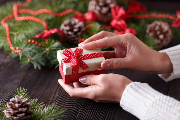 Hands holding a gift box with a pine cone background