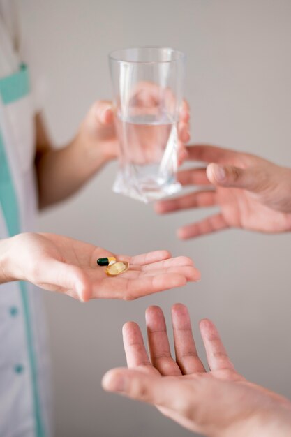Hands holding glass of water and pills