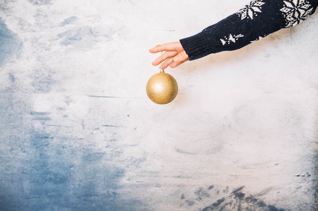 Hands holding a golden christmas ball