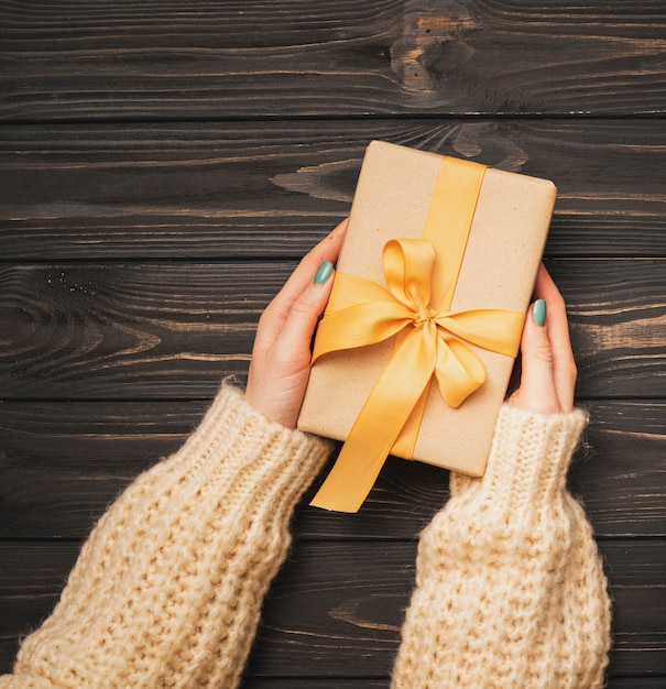 Hands holding golden ribbon tied present for christmas