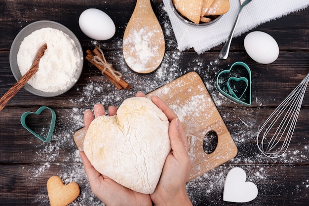 Free photo hands holding heart-shaped dough