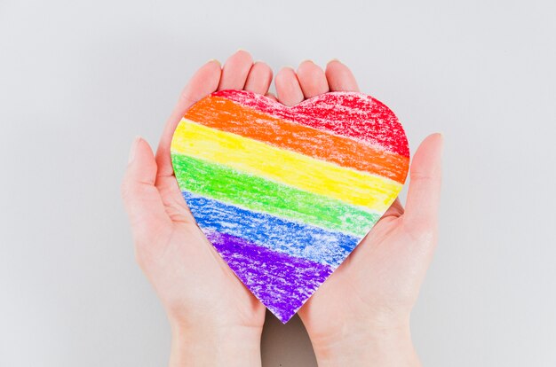 Hands holding a heart with pride day flag colors