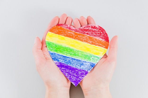 Hands holding a heart with pride day flag colors