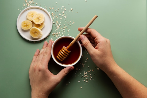 Hands holding honey dipper and bowl