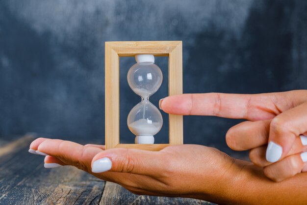 Hands holding hourglass and showing time