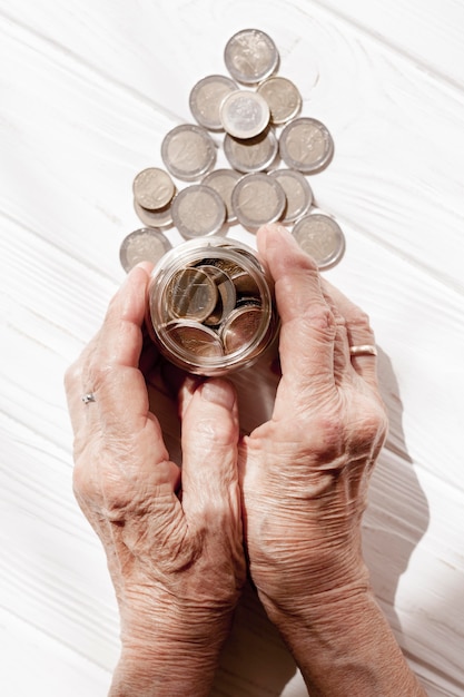 Free photo hands holding a jar filled with coins top view