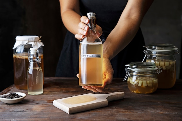 Free photo hands holding kombucha bottle front view