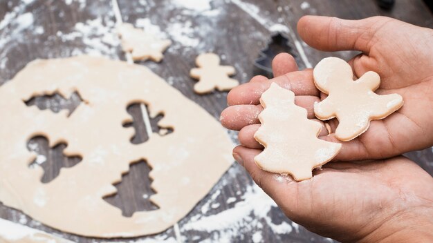 Hands holding man and Christmas tree shaped pastry
