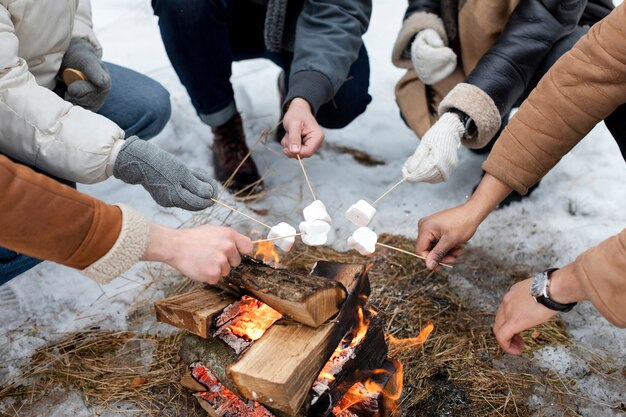 Mani che tengono marshmallow vicino al fuoco