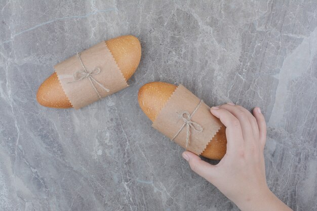 Hands holding a mini bread on marble surface