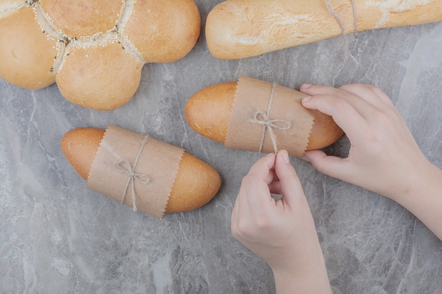 Free photo hands holding a mini bread on marble surface