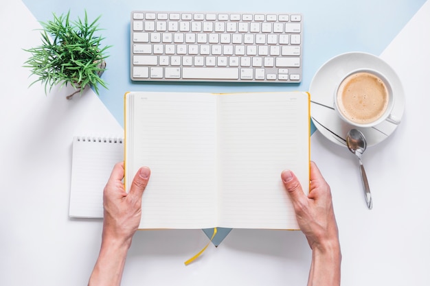 Hands holding opened diary on desk