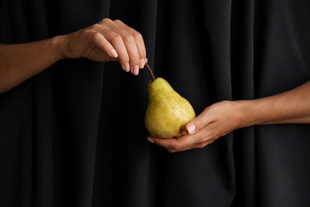 Hands holding pear with dark background