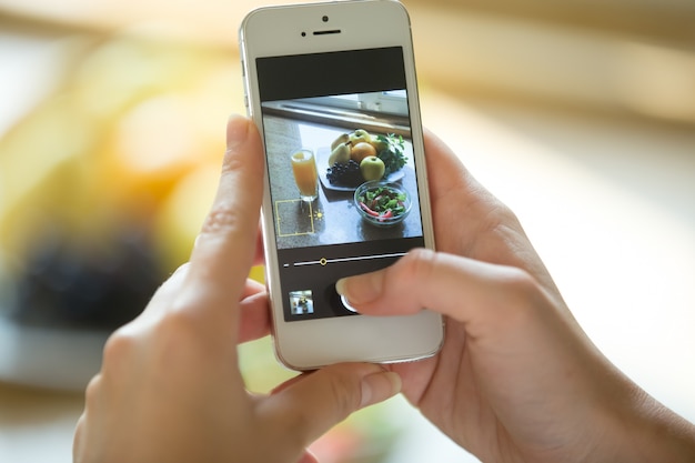 食べ物の写真を携帯電話で手に持っている手