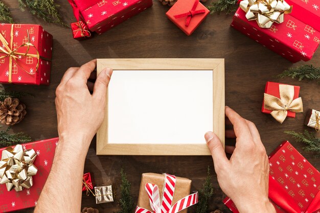 Hands holding photo frame between gift boxes