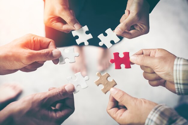 Hands holding piece of blank jigsaw puzzle for teamwork workplace success and strategy concept.