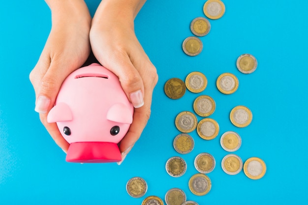 Free photo hands holding piggy bank on table with coins