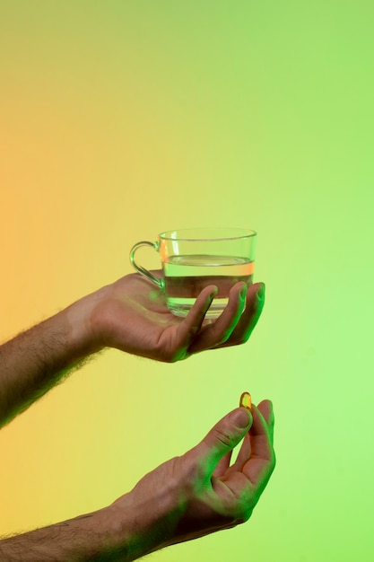 Бесплатное фото Руки держат таблетку с водой на градиентном фоне