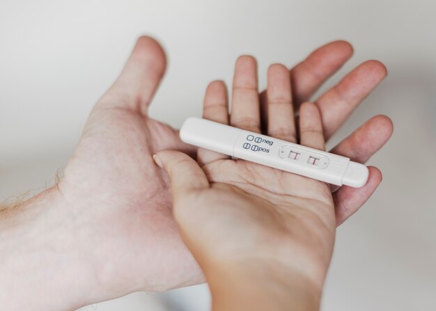 긍정적 인 임신 테스트를 잡고 손