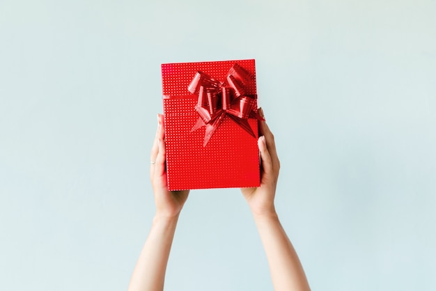 Hands holding red gift on plain background