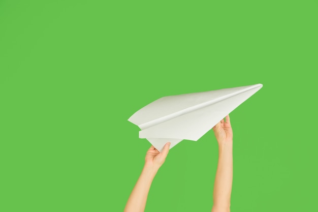 Free photo hands holding the sign of paper airplane or message on green  background.